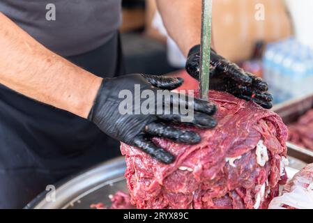 Le maître prépare du kebab turc à cuire à partir de viande rouge, de viande de doner kebab non cuite, de gyros grecs à la broche dans un restaurant . Photo de haute qualité Banque D'Images