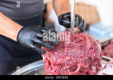 Le maître prépare du kebab turc à cuire à partir de viande rouge, de viande de doner kebab non cuite, de gyros grecs à la broche dans un restaurant . Photo de haute qualité Banque D'Images