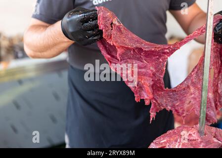 Le maître prépare du kebab turc à cuire à partir de viande rouge, de viande de doner kebab non cuite, de gyros grecs à la broche dans un restaurant . Photo de haute qualité Banque D'Images