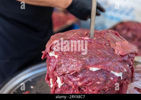 Le maître prépare du kebab turc à cuire à partir de viande rouge, de viande de doner kebab non cuite, de gyros grecs à la broche dans un restaurant . Photo de haute qualité Banque D'Images