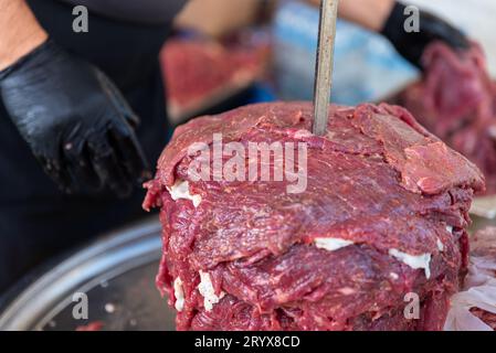 Le maître prépare du kebab turc à cuire à partir de viande rouge, de viande de doner kebab non cuite, de gyros grecs à la broche dans un restaurant . Photo de haute qualité Banque D'Images