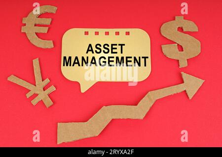 Concept commercial. Sur la surface rouge, il y a des symboles d'argent, une flèche et un signe avec l'inscription - Asset Management Banque D'Images