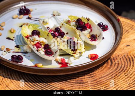 Hors-d'œuvre végétariens préparés avec des bateaux d'endives belges frais farcis de pignons grillés, fromage bleu, baies de porc fraîches et huile d'olive fraîche garnie Banque D'Images