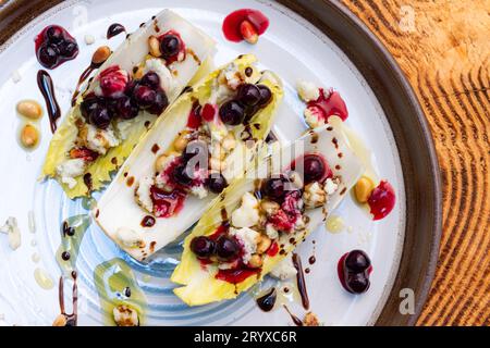 Hors-d'œuvre végétariens préparés avec des bateaux d'endives belges frais farcis de pignons grillés, fromage bleu, baies de porc fraîches et huile d'olive fraîche garnie Banque D'Images