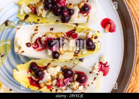 Hors-d'œuvre végétariens préparés avec des bateaux d'endives belges frais farcis de pignons grillés, fromage bleu, baies de porc fraîches et huile d'olive fraîche garnie Banque D'Images