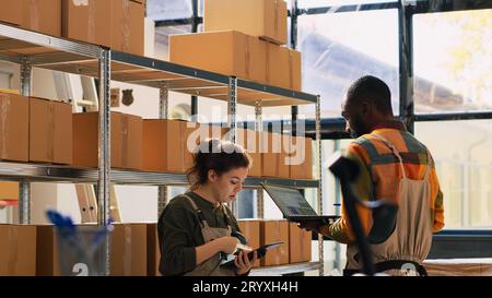 L'équipe de la salle d'entreposage vérifie les produits dans les boîtes en carton et compte les colis de marchandises avant d'expédier les commandes. Jeunes gens divers travaillant dans l'entrepôt, faisant l'inventaire. Prise de vue à main levée. Banque D'Images