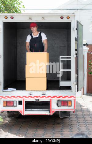 Livreur avec des boîtes dans le camion, la livraison et le concept logistique Banque D'Images