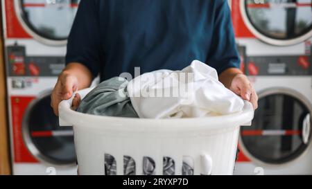 Mari de la maison avec panier et vêtements sales ou lavés à laundryÂ intérieur de la buanderie. lavage machineÂ à l'entreprise de blanchisserie stor Banque D'Images