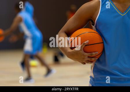 Divers joueurs de basket-ball masculins portant des vêtements de sport bleus et jouant au basket-ball à la salle de gym Banque D'Images