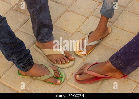Les pieds de quatre jeunes garçons sur la rue Dehli tous avec différentes tongs de couleur Banque D'Images