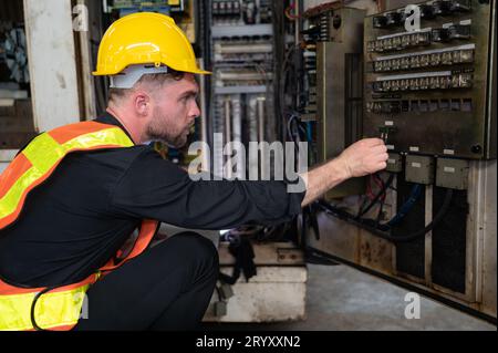 L'ingénieur inspecte le système électrique et répare le système mécanique dans l'armoire de commande de la machine. pour le m Banque D'Images