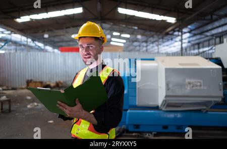 Les ingénieurs mécaniciens entrent dans l'ancien entrepôt de machines pour inspecter et réparer les machines usagées avec le personnel de l'entrepôt. Banque D'Images