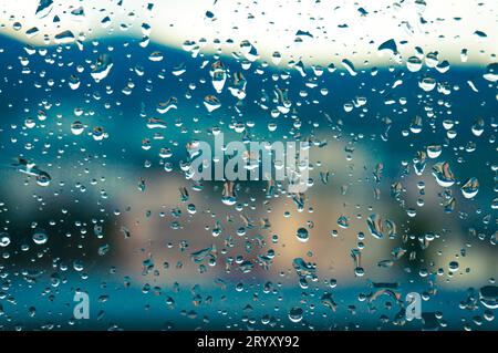 Gouttes de pluie sur la surface des verres de fenêtre avec coucher de soleil. Gouttes sur le verre pulvérisé sur l'arrière-plan de la fenêtre pour la mise au point sélective de vue sombre textÂ Banque D'Images