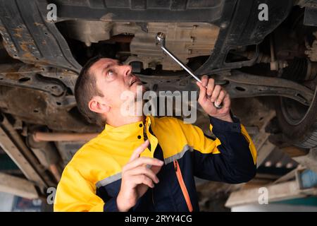 Mécanicien de réparation automobile le train roulant de la voiture est inspecté pour les dommages causés par de lourdes collisions. Banque D'Images