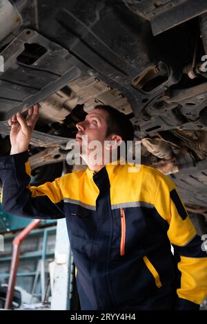 Mécanicien de réparation automobile le train roulant de la voiture est inspecté pour les dommages causés par de lourdes collisions. Banque D'Images