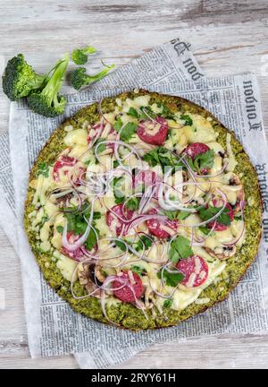 Les glucides à faible base de brocoli croûte à pizza au salami céto, avocat sur vintage newspapper. Vue d'en haut Banque D'Images