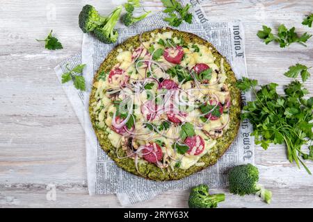 Les glucides à faible base de brocoli croûte à pizza au salami céto, avocat sur vintage newspapper. Vue d'en haut Banque D'Images