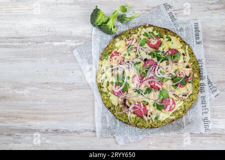 Les glucides à faible base de brocoli croûte à pizza au salami céto, avocat sur vintage newspapper. Vue d'en haut Banque D'Images