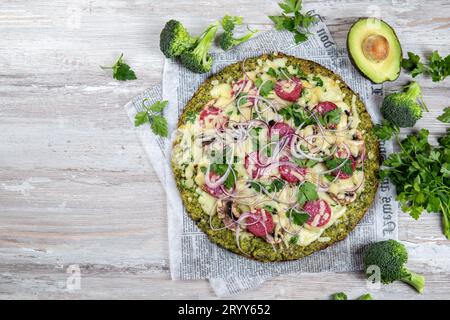 Les glucides à faible base de brocoli croûte à pizza au salami céto, avocat sur vintage newspapper. Vue d'en haut Banque D'Images