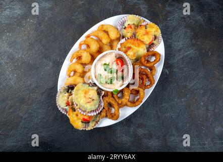 La nourriture péruvienne. Piqueo caliente. Fun pour plateau de fruits de mer crevettes frites, calamars cuits et anneaux de pétoncles avec sauce Banque D'Images