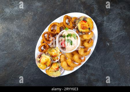 La nourriture péruvienne. Piqueo caliente. Fun pour plateau de fruits de mer crevettes frites, calamars cuits et anneaux de pétoncles avec sauce Banque D'Images