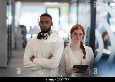 Dans un bureau moderne, jeune homme d'affaires afro-américain et sa collègue femme d'affaires, avec ses cheveux orange frappants, s'engagent dans Banque D'Images