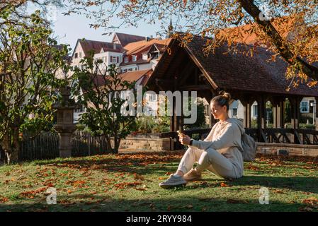 Jeune fille adolescente à la mode avec smartphone dans Europian Park en automne assis à sourire. Tendance Jeune femme à l'automne dans le parc Banque D'Images