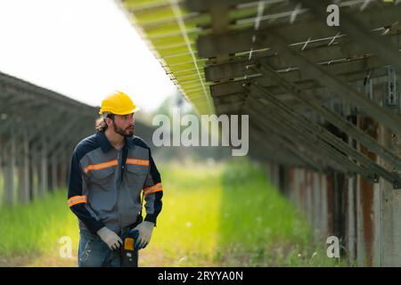 Les ingénieurs électriciens inspectent et entretiennent des cellules solaires à un panneau de cellules solaires au milieu d'une centaine d'acres d'herbe. Banque D'Images