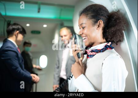Agent de bord parlant à travers un haut-parleur pour accueillir les passagers et donner des conseils sur les voyages en avion Banque D'Images
