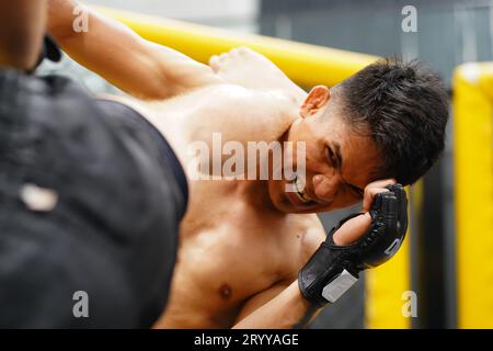 Art martial mixte, Un boxeur avec l'arme de coup de pied le cou la gorge de l'adversaire. Banque D'Images