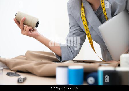 Gros plan de la main couturière tenant la bobine de styliste de fil designer dans l'atelier de propriétaire d'entreprise. Concept de tailleur et de couture. Portr Banque D'Images