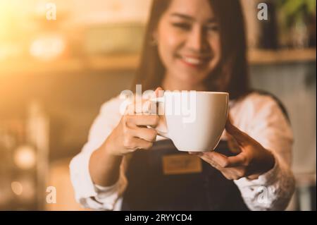 Gros plan de tasse à café blanc avec beau fond de barista femme asiatique pour servir au client. Emploi et profession. Alimentation et Banque D'Images
