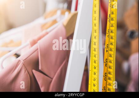 Gros plan du ruban à mesurer et à la ligne de la mode femme de couleur rose pastel shirts avec cintres en bois dans la boutique de vêtements. Banque D'Images