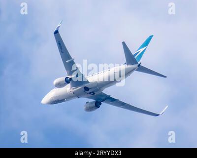 Calgary, Alberta, Canada. 25 juillet 2023. Vue de bas en haut d'un avion WestJet décollant pendant la journée. Banque D'Images