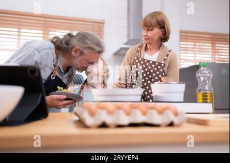 Les grands-parents avec leurs petits-enfants et leurs enfants se réunissent dans la cuisine pour préparer le dîner de la journée. Banque D'Images