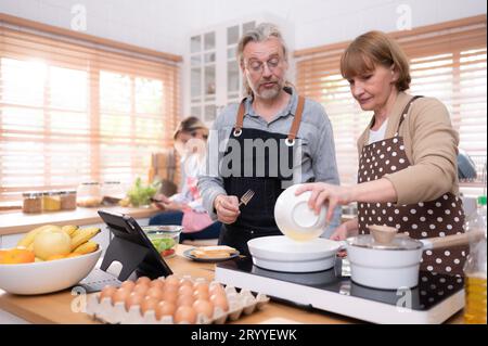 Les grands-parents avec leurs petits-enfants et leur fille se réunissent dans la cuisine pour préparer le dîner de la journée. Banque D'Images