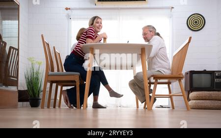 Le père, la mère et la fille sont ravis de dîner ensemble à la table familiale. Banque D'Images