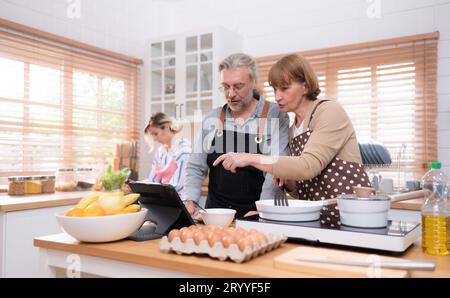 Les grands-parents avec leurs petits-enfants et leur fille se réunissent dans la cuisine pour préparer le dîner de la journée. Banque D'Images