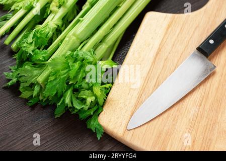 Bouquet de tige de céleri frais sur une table en bois et planche à découper et couteau avec des feuilles. Nourriture et ingrédients de légumes sains. Banque D'Images