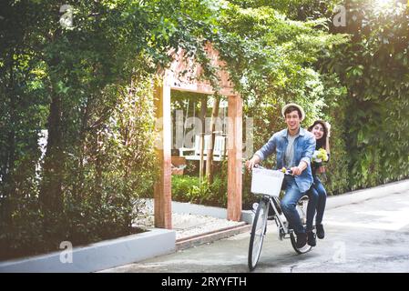 Couple heureux à vélo ensemble dans le fond romantique de parc de vue. Concept de lune de miel pour la Saint-Valentin et le mariage. Personnes et Banque D'Images