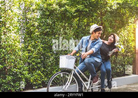 Couple heureux à vélo ensemble dans le fond romantique de parc de vue. Concept de lune de miel pour la Saint-Valentin et le mariage. Personnes et Banque D'Images