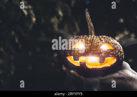 Citrouille d'Halloween à la main.Concept de vacances et de religion.Fantôme sur le thème de la citrouille.Sorcellerie et thème de mystère. Banque D'Images