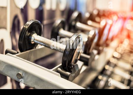 Gros plan de l'ensemble d'haltères en acier métallique noir. Haltères sur rack dans le centre de fitness sportif. Entraînement physique et fitness Banque D'Images