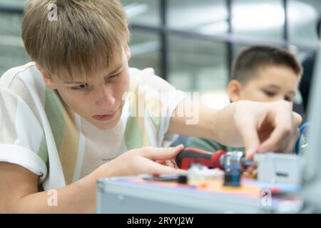 Les jeunes utilisant la technologie de robot de main s'amusent à apprendre la carte de circuit électronique et le contrôleur de robot de main de Banque D'Images