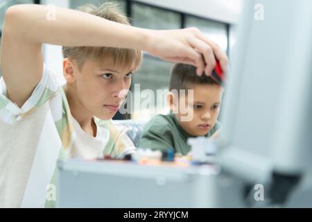 Les jeunes utilisant la technologie de robot de main s'amusent à apprendre la carte de circuit électronique et le contrôleur de robot de main de Banque D'Images