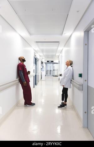 Divers médecins masculins et féminins tenant du café à emporter dans le couloir de l'hôpital Banque D'Images