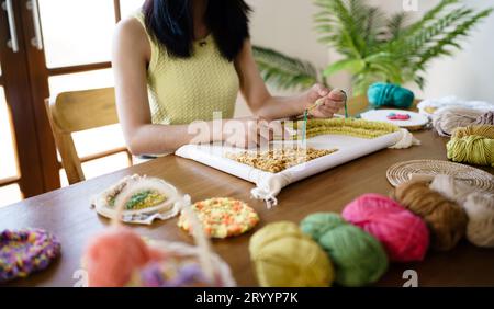 Aiguille perforée. Femme asiatique faisant tricoter Hobby à la main dans l'atelier de studio. Designer Workplace projet artisanal fait main DIY embro Banque D'Images