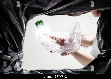 Image de l'intérieur du sac de recyclage jaune d'un homme jetant une bouteille en plastique vide dans un bac de recyclage Home recycle éco vert zéro concept Banque D'Images