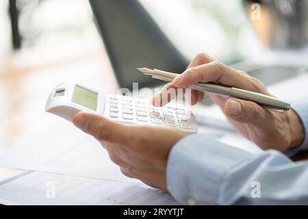 Homme d'affaires comptable analysant les graphiques d'investissement facture et appuyant sur les boutons de calculatrice sur les documents. Comptable comptable Banque D'Images