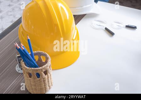 Vue de dessus du bureau du projet d'ingénierie dans le chantier de construction ou bureau avec papeterie et casque de sécurité jaune. Construction A. Banque D'Images